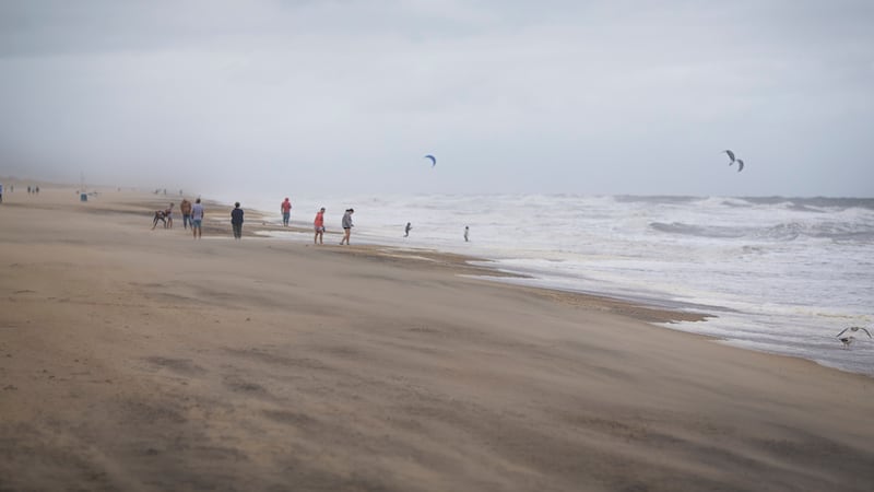 Un grupo de bañistas mira a gente haciendo kitesurf entre las olas provocadas por la tormenta...