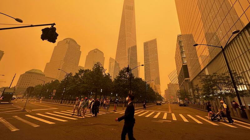 Peatones pasan junto al One World Trade Center (centro), en medio de la humareda causada por...